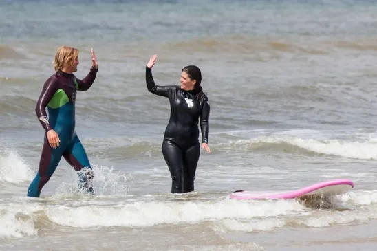 Instructeur geeft high 5 na surfles texel