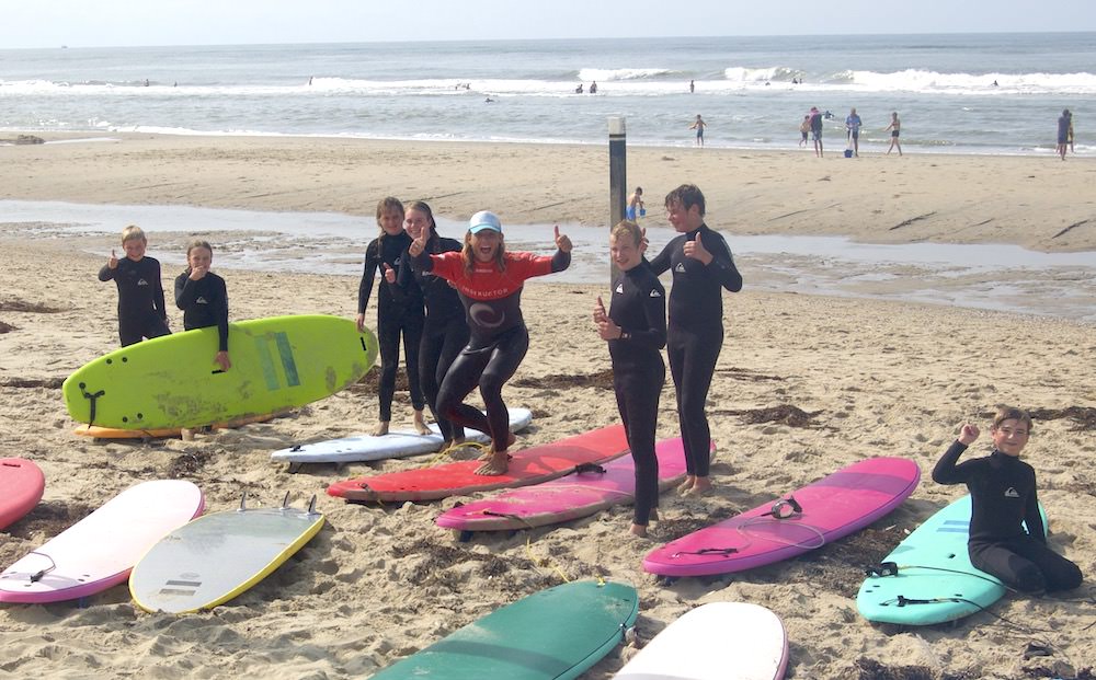 Kids juichen met instructeur tijdens de surfles